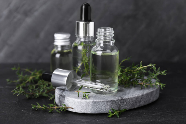 Natural thyme essential oil on black table - Фото, изображение