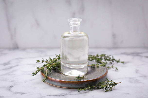 Thyme essential oil on white marble table - Fotografie, Obrázek
