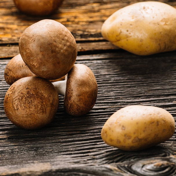 Verschillende verse champignons champignons op oude houten ondergrond, selectieve focus - Foto, afbeelding
