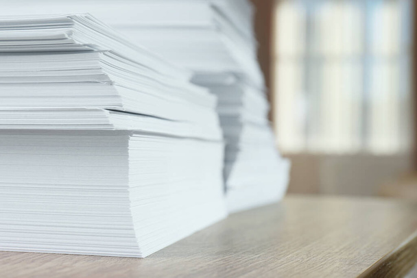 Stacks of paper sheets on wooden table against blurred background, closeup. Space for text - Φωτογραφία, εικόνα