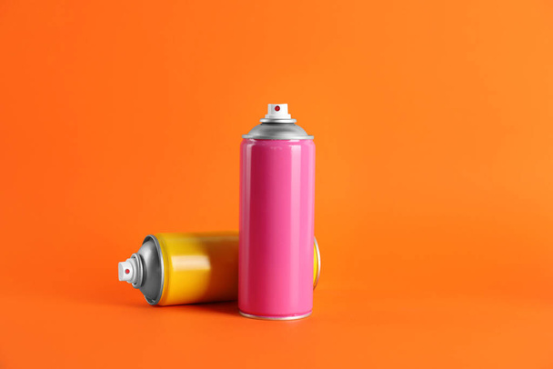 Colorful cans of spray paints on orange background. Space for text - Foto, imagen