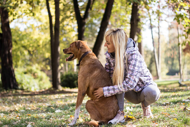 νεαρή γυναίκα που αγκαλιάζουν το σκύλο - Φωτογραφία, εικόνα