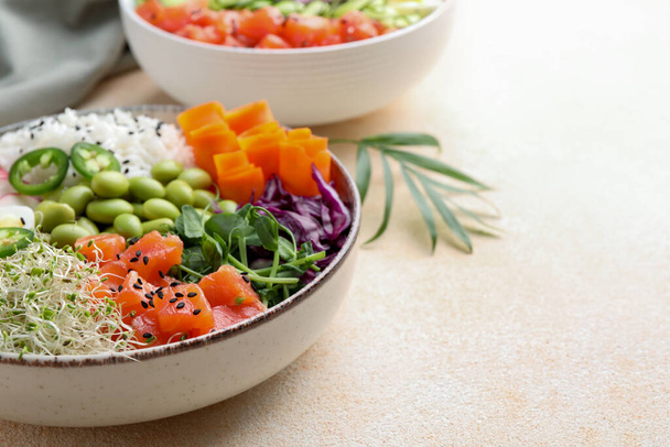 Delicious poke bowls with vegetables, fish and edamame beans on light table, closeup. Space for text - 写真・画像
