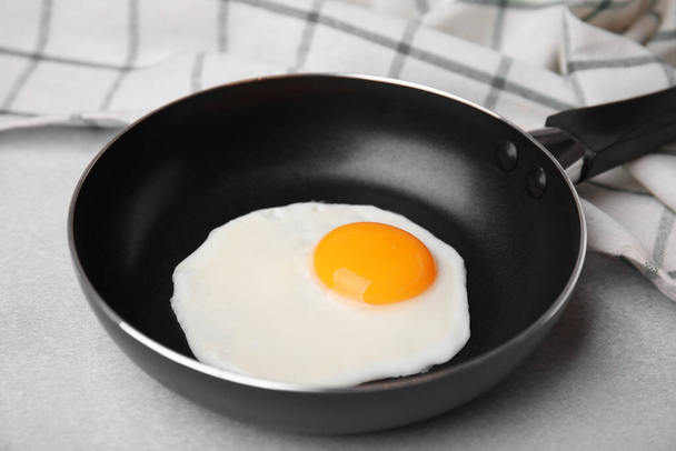 Tasty fried egg in pan on light grey table, closeup - Zdjęcie, obraz