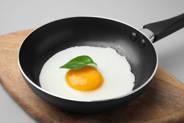 Pan with tasty fried egg on light grey background, closeup - Фото, изображение