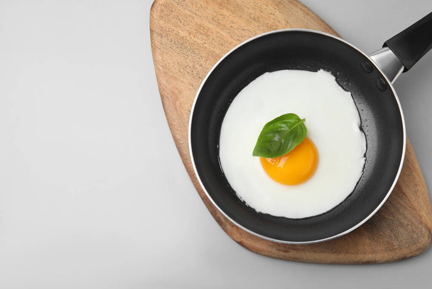 Pan with tasty fried egg on light grey background, top view. Space for text - Фото, изображение