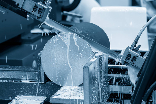 A operação da máquina de corte de serra de fita cortando as peças do eixo de metal com método de refrigeração. A máquina-ferramenta para fins industriais. - Foto, Imagem