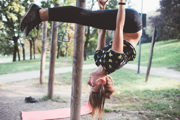 Urheilullinen istuvuus nuori nainen harjoittelee akrobaattista joogaa voimaa ja tasapainoa varten ulkoilupuistossa - Valokuva, kuva