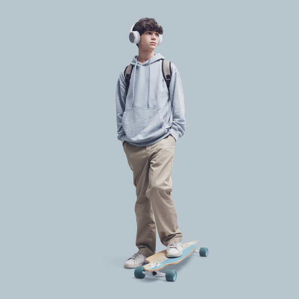 Cool teenager posing with a skateboard, isolated on gray background - Фото, зображення