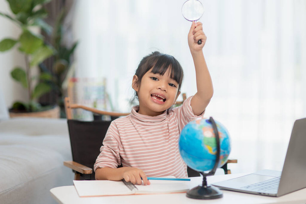 Azjatycka dziewczynka uczy się modelu globu, koncepcji ratowania świata i uczenia się poprzez zabawę dla edukacji dzieci w domu. - Zdjęcie, obraz