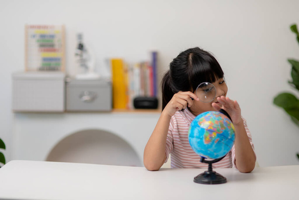 Asiática niña está aprendiendo el modelo de globo, concepto de salvar el mundo y aprender a través de la actividad de juego para la educación de los niños en el hogar. - Foto, Imagen