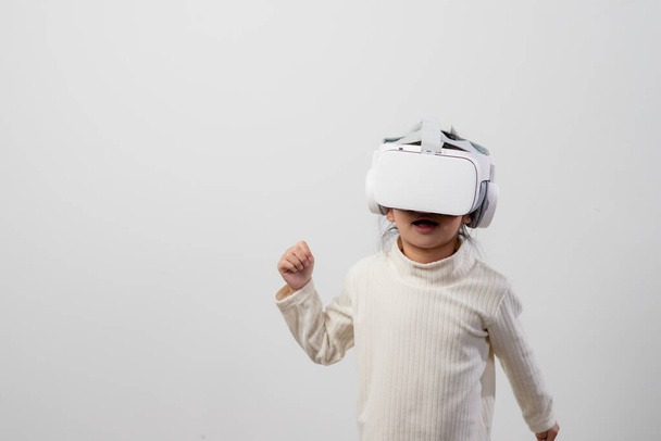 Niña asiática con auriculares de realidad virtual. Tecnología de la innovación y concepto educativo - Foto, Imagen
