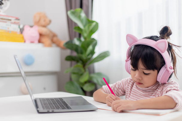 Ázsiai kislány fejhallgató van video hívás távoli osztály tanár segítségével laptop, tanulmány online számítógépen, magániskola koncepció - Fotó, kép