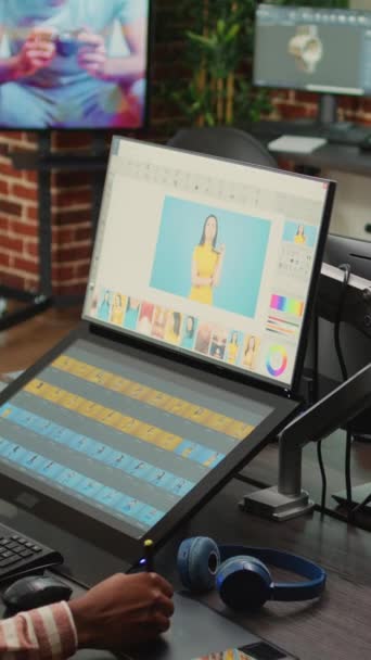 Dikey video: Genç içerik yaratıcısı dokunmatik ekran monitörü ve stil kullanarak renk derecelendirme ile fotoğrafları rötuşluyor. Ajansta resim rötuşlamak için düzenleme yazılımı kullanan grafik tabletli resim düzenleyici - Video, Çekim