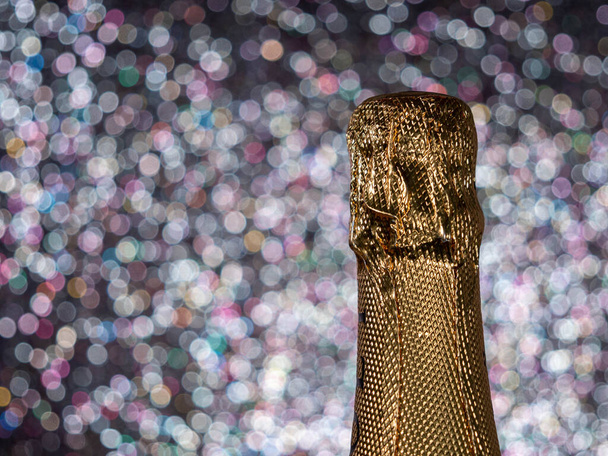Eine Flasche Champagner mit Goldglitzern auf glänzendem Hintergrund. Spaßparty - Foto, Bild