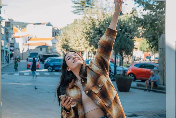 gelukkig meisje in de straat met telefoon vieren opgewonden - Foto, afbeelding