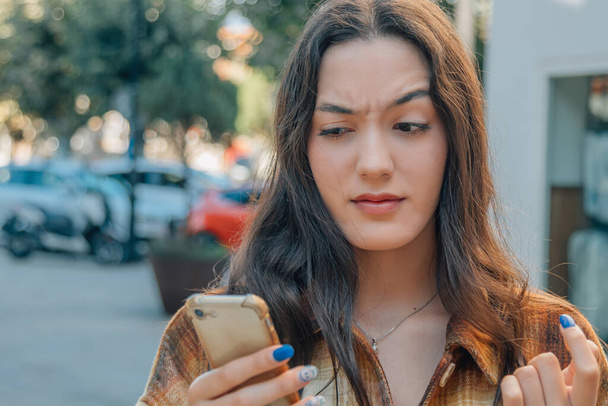 nainen, jolla on matkapuhelin ja ilmaus epäluottamusta tai epäilystä - Valokuva, kuva