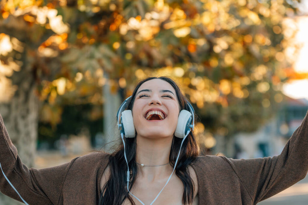 tyttö syksyllä innoissaan onnea kuulokkeet ja matkapuhelin - Valokuva, kuva