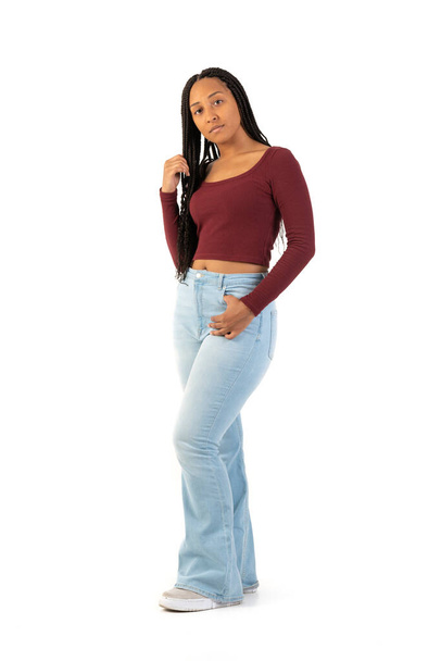 Portrait of young black woman with maroon shirt and jeans on a white background in studio - Foto, immagini
