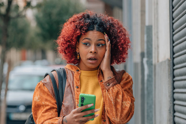 девушка или женщина на улице с мобильным телефоном и беспокойным выражением - Фото, изображение