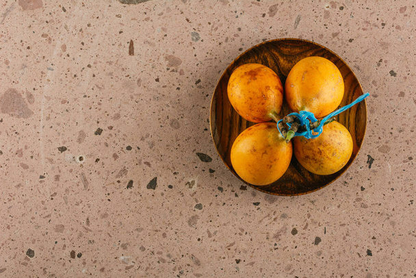 Frutta di stagione invernale in Messico, granate di muco su un piatto di legno su fondo di cava rosa. - Foto, immagini