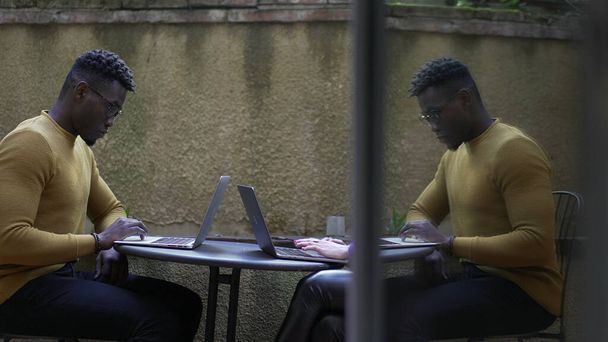 Чёрный африканский мужчина с ноутбуком снаружи, работает на улице - Фото, изображение