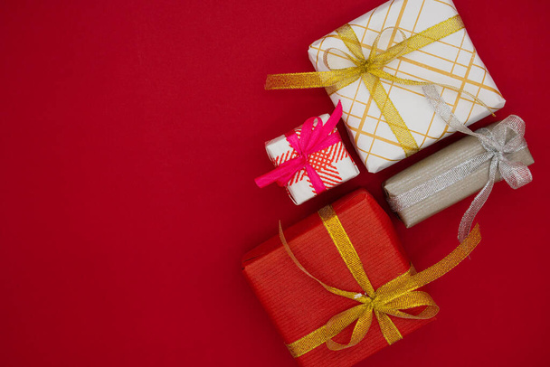 Τέσσερα χριστουγεννιάτικα κουτιά με δώρα σε κόκκινο φόντο. Χριστούγεννα και το νέο έτος έννοια. Στο πάνω μέρος. Θέση για κείμενο. - Φωτογραφία, εικόνα