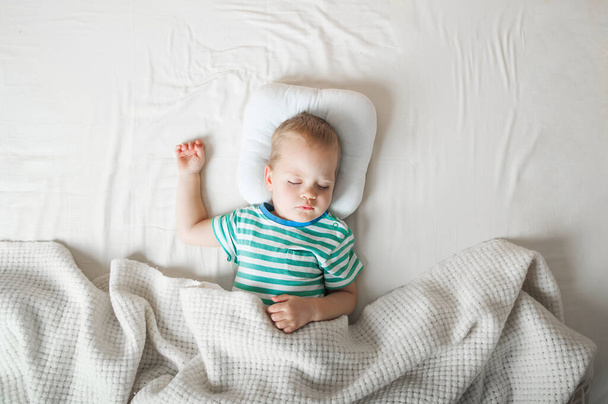 Kleinkind, das in Großaufnahme auf dem Bett schläft. Gesundheitskonzept. - Foto, Bild