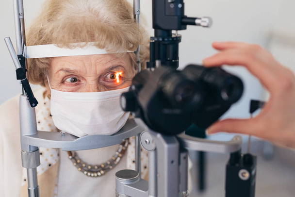 Old woman looking at an optical instrument - Foto, afbeelding