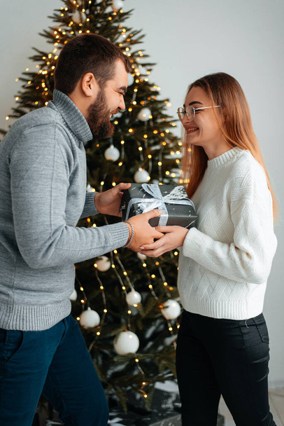 Cute, young couple exchanging Christmas gifts for Christmas morning. - Valokuva, kuva
