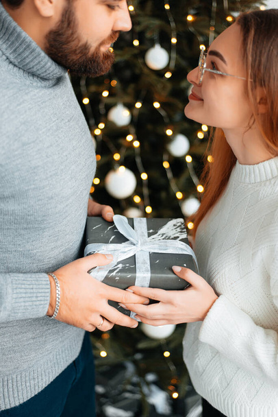 Cute, young couple exchanging Christmas gifts for Christmas morning. - Foto, Imagen