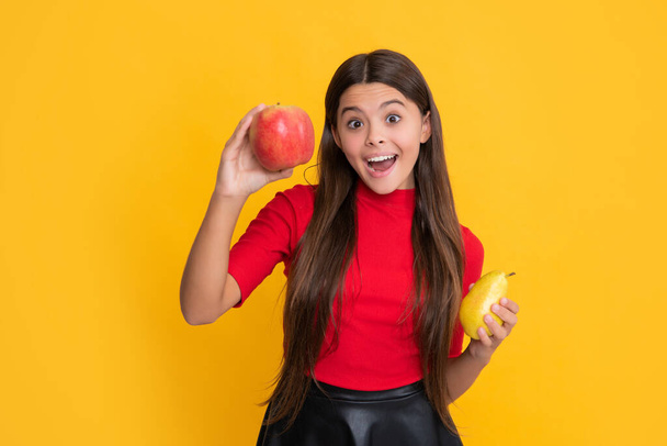 smiling amazed child hold apple and pear on yellow background. - Valokuva, kuva