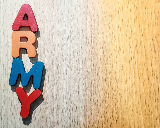 Fotografie abecedy na dřevěném stole s nápisem ARMY. Armáda je fandom populární KPOP skupiny BTS, která je zkratkou pro rozkošný zástupce M.C pro mládež. - Fotografie, Obrázek