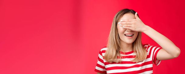 Close-up lucky cute asian blond woman smiling broadly count ten promise not peek, cover eyes with palm grinning awaiting surprise b-day party gift, stand red background anticipating. - Photo, Image