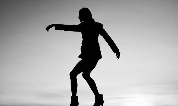 female silhouette on sunset sky background of dancing woman, silhouette. - 写真・画像