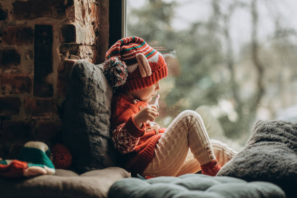 The kid sits at the window and waits for Santa Claus. Waiting for the Christmas holidays. Happy childhood. Waiting for firefighters. - Foto, Imagem