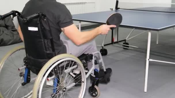 Pyörätuolissa istuva poika pelaa pöytätennistä. Vammaisten urheilua. 4k-video - Materiaali, video