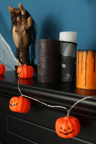 Jack-o'-lanterns and candles on black fireplace near blue wall - Foto, immagini