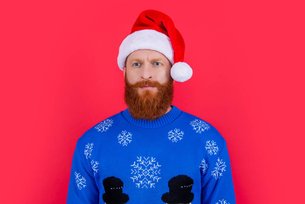 have a merry xmas. caucasian serious man in xmas sweater and santa hat isolated on red background. man at xmas party. - Photo, image