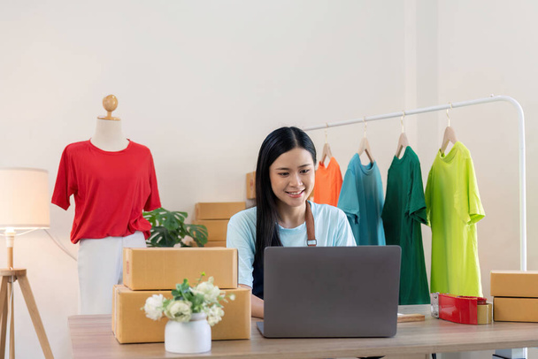 Young successful asian woman doing clothing business by open shop and selling online. she using laptop computer. online sell marketing delivery, SME e-commerce telemarketing concept. - Photo, Image