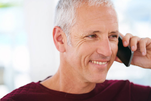 A desfrutar de uma boa e velha conversa. um homem maduro sorridente falando em um celular em sua sala de estar - Foto, Imagem