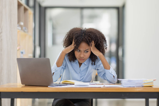 Afrykańska amerykańska rodzina zestresowana podczas pracy na laptopie, zmęczona smutna kobieta z bólem głowy czująca się chora w biurze.  - Zdjęcie, obraz