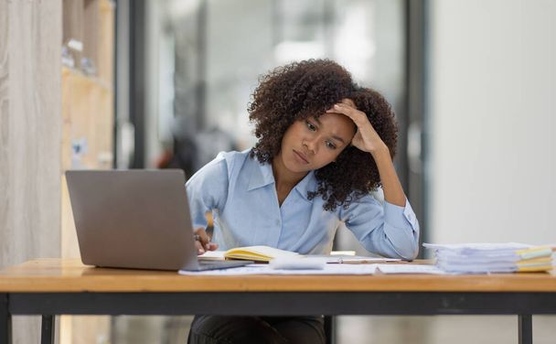 familia afroamericana estresada mientras trabajaba en el ordenador portátil, mujer triste cansado con dolor de cabeza sensación de malestar en el lugar de trabajo espacio de copia de la oficina.  - Foto, imagen