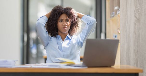 アフリカ系アメリカ人の家族はノートパソコンで仕事をしながらストレスを感じ、職場のコピースペースで頭痛の種を感じる疲れた悲しい女性.  - 写真・画像