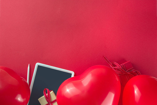 Valentýn sladká dovolená pozadí s červeným srdcem ve tvaru balónky na červeném pozadí, s notepad, tablet, flatlay horní pohled rám kopírovat prostor, maketa up pro valentýnské přání - Fotografie, Obrázek