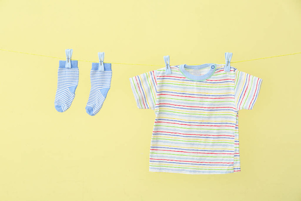 Baby vestiti appesi sulla linea di lavanderia contro sfondo giallo - Foto, immagini