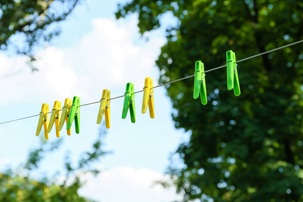Muchos pinzas de ropa de colores que cuelgan de la cuerda al aire libre - Foto, imagen