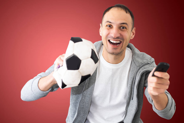 αρσενικό ανεμιστήρα ποδοσφαίρου με μια τσαλακωμένη μπάλα και τηλεχειριστήριο. - Φωτογραφία, εικόνα