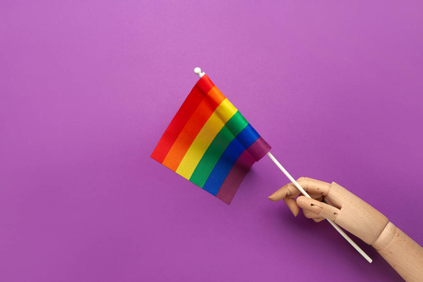Wooden hand with LGBT flag on purple background - Photo, Image