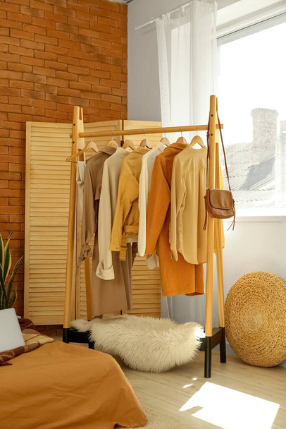 Стойка со стильной одеждой в интерьере современной спальни - Фото, изображение